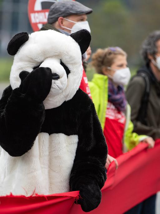 Ein als Panda verkleideter Umweltaktivist steht bei einer Demonstration für mehr Klimaschutz vor dem Bundeskanzleramt in einer Menschenkette.