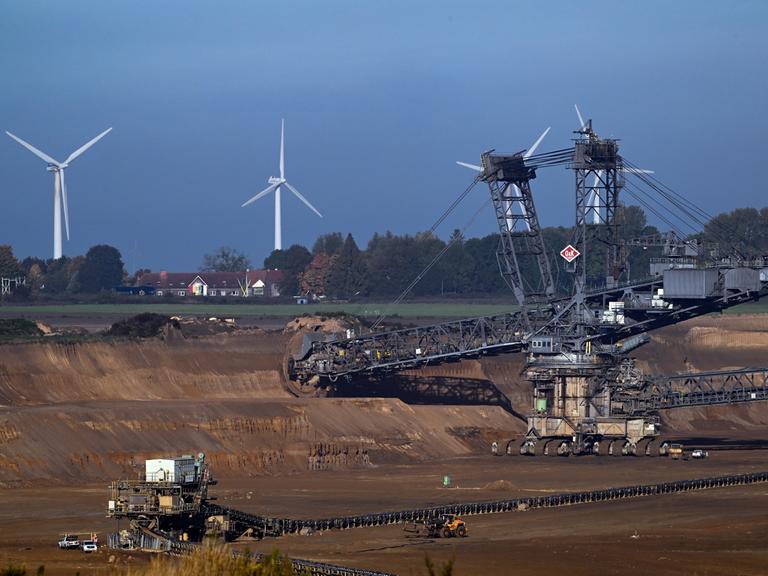 Ein Schaufelradbagger arbeitet im Braunkohletagebau Garzweiler. Im Hintergrund ist die Ortschaft Lützerath zu sehen.