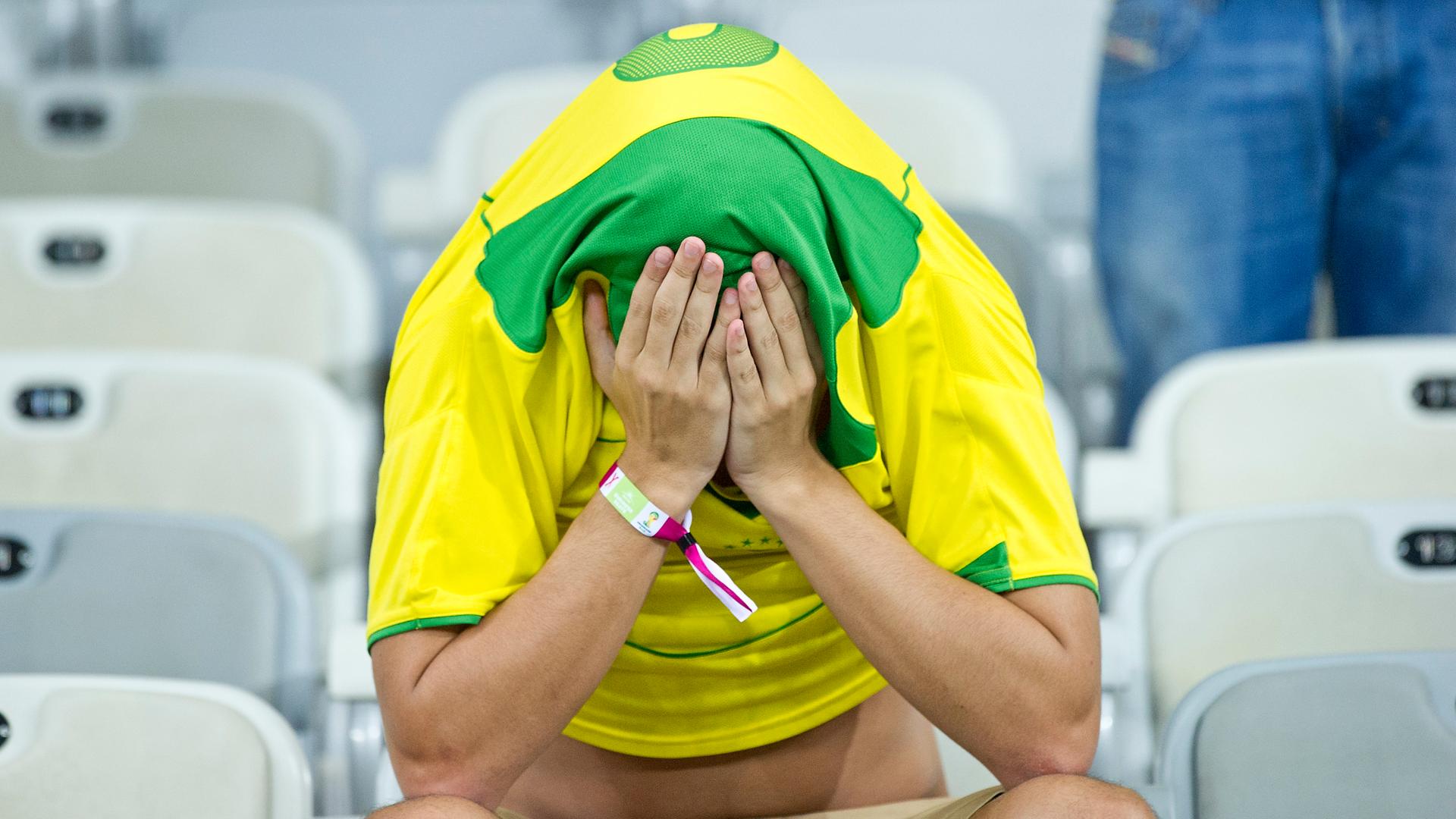 Ein brasilianischer Fan hat das Trikot über den Kopf gezogen und das Gesicht in den Händen vergraben.