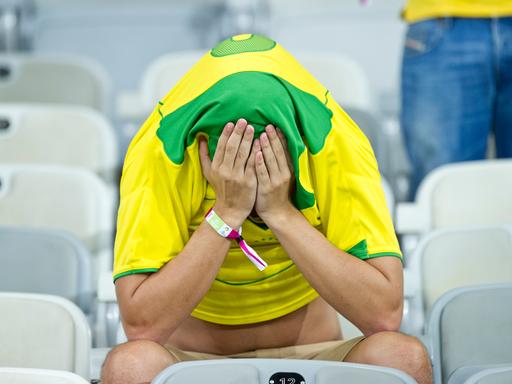 Ein brasilianischer Fan hat das Trikot über den Kopf gezogen und das Gesicht in den Händen vergraben.