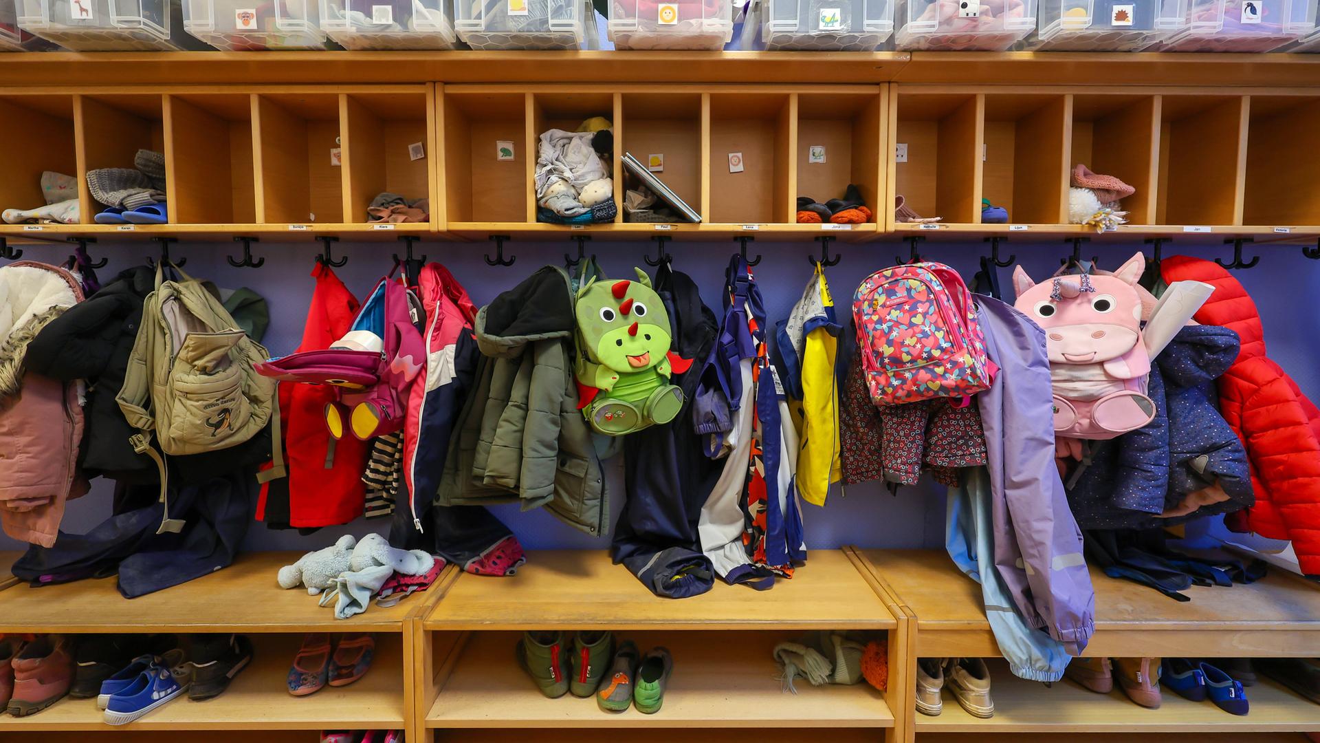 Zahlreiche Kinderjacken hängen nebeneinander, darüber und darunter Holzfächer für Gegenstände und Schuhe der Kinder