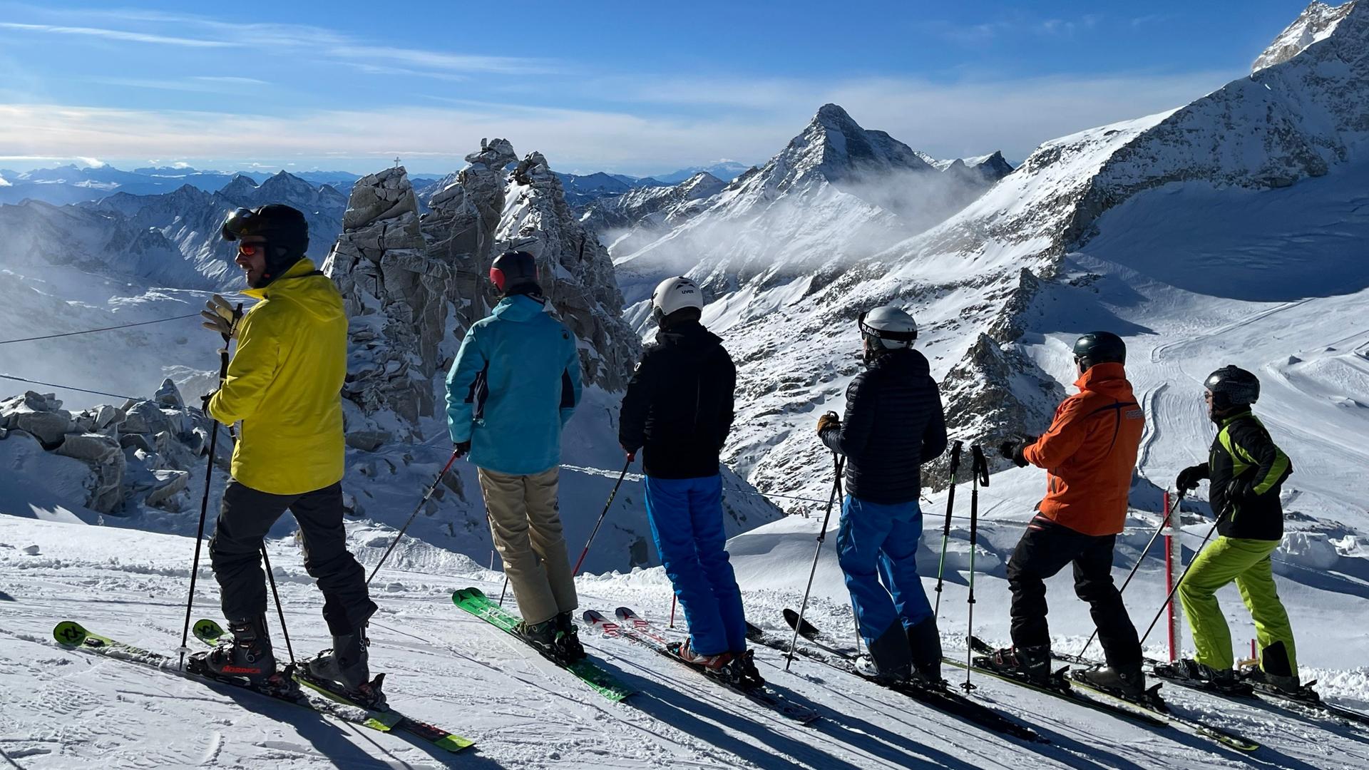 Wintersportler stehen auf dem Hintertuxer Gletscher und schauen Richtung Schlegeisspeicher