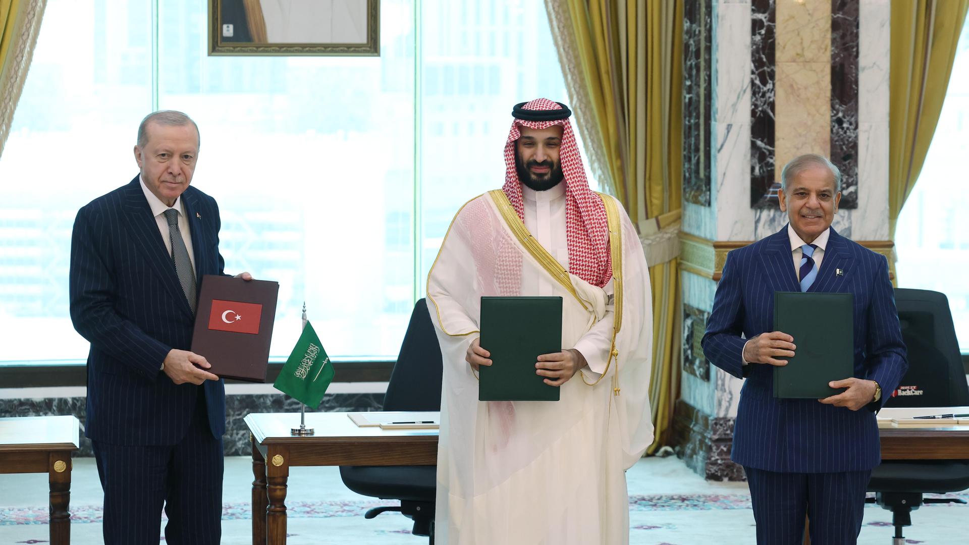 Der saudi-arabische Kronprinz bin Salman (m.), der türkische Präsident Erdogan(l.) und der pakistanische Premierminister Sharif stehen nebeneinander und halten Dokumente in den Händen.