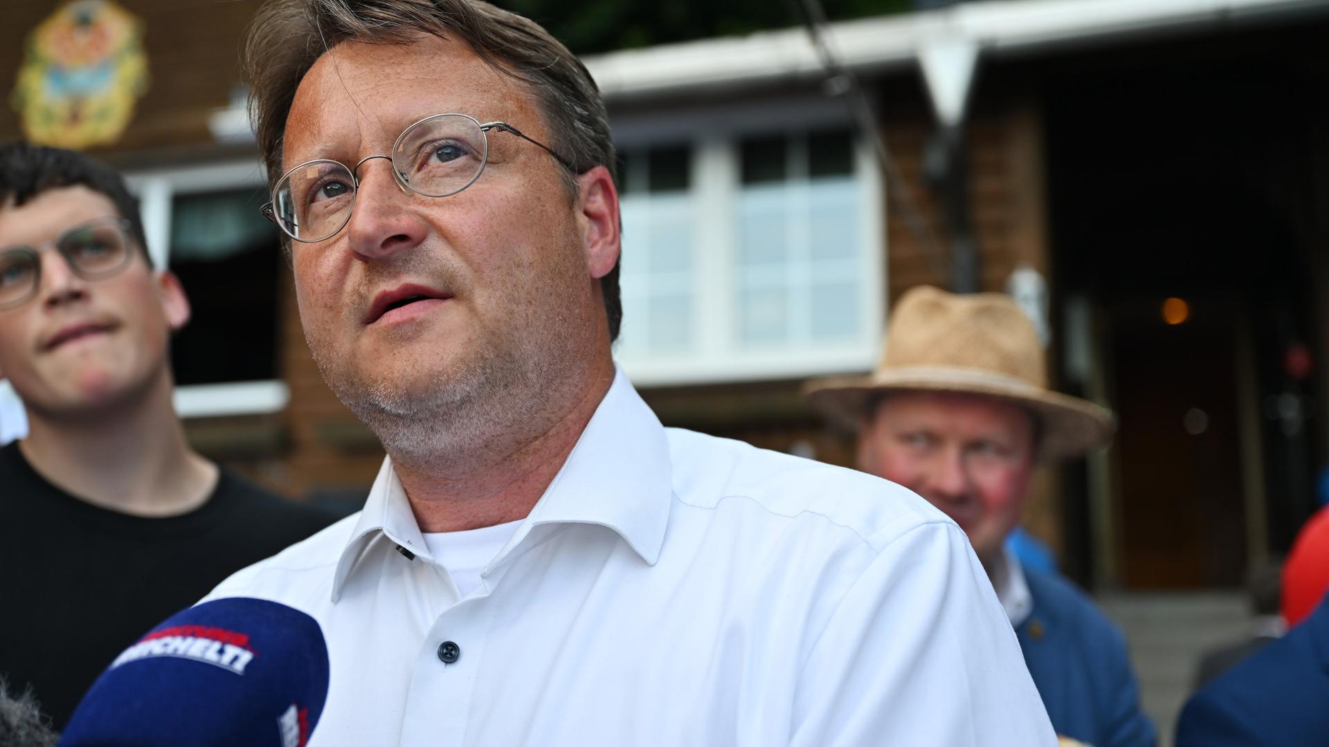 Der Wahlsieger des Thüringer Landkreises Sonneberg, Robert Sesselmann (AfD), steht vor einem Mikrofon und schaut nach oben.