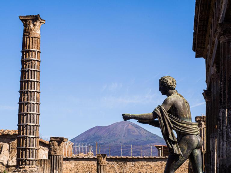 Statue des Apollo in der antiken Stadt Pompeji, Kampanien, im Hintergrund der Vulkan Vesuv