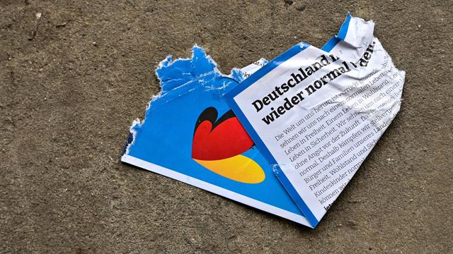 Auf dem Fussboden liegt ein zertretener, kaputter AfD-Flyer aus dem Bundeswahlkampf.