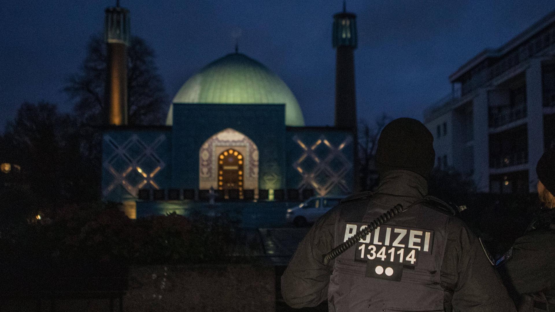 Im Morgengrauen steht ein Polizist vor einer Moschee des "Islamischen Zentums Hamburg".