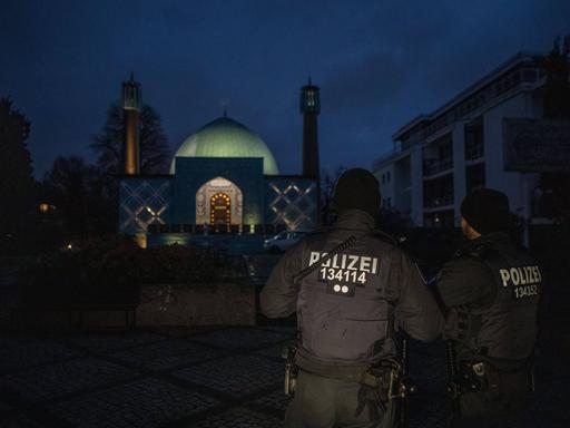 Im Morgengrauen steht ein Polizist vor einer Moschee des "Islamischen Zentums Hamburg".