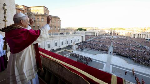Papst Leo XIV. steht auf dem Balkon des Petersdoms und spricht zu einer großen Menschenmenge.