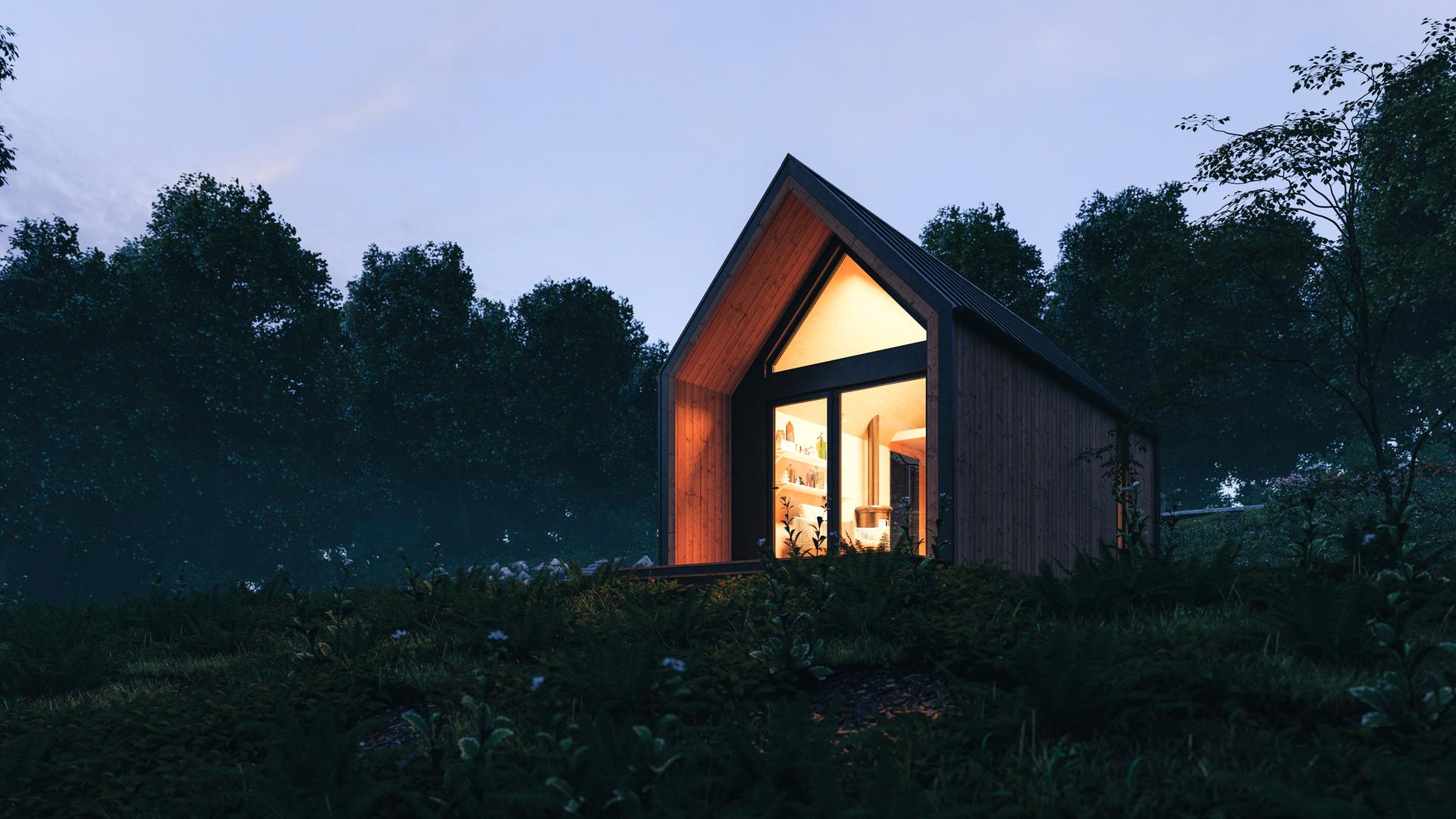 Nachtaufnahme eines von innen beleuchtenden Tiny Houses auf einer Wiese