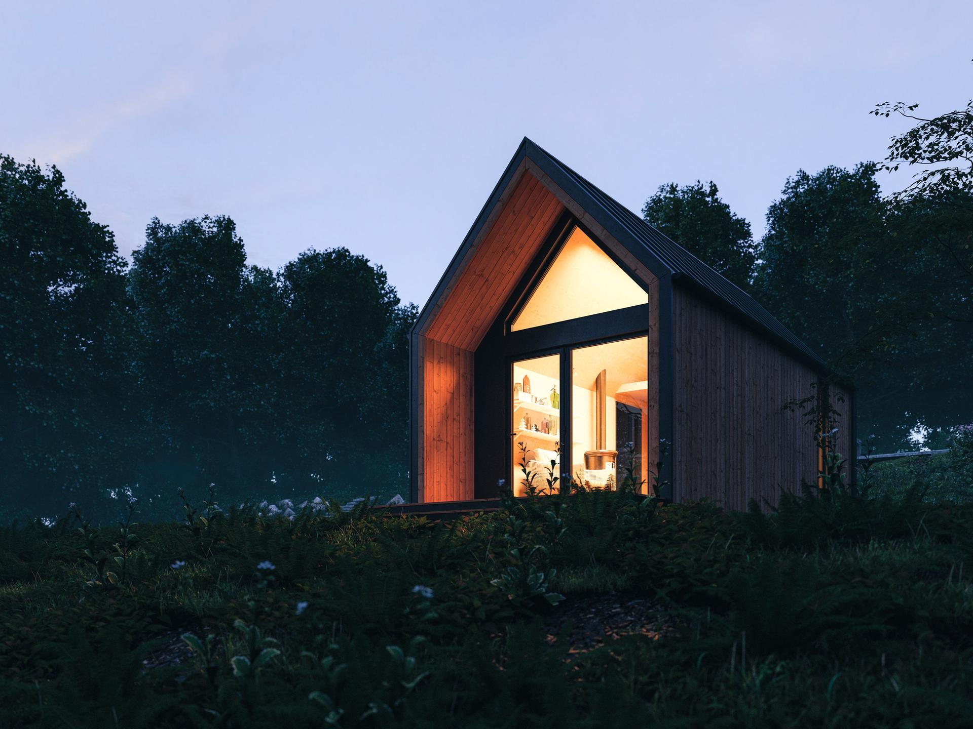 Nachtaufnahme eines von innen beleuchtenden Tiny Houses auf einer Wiese