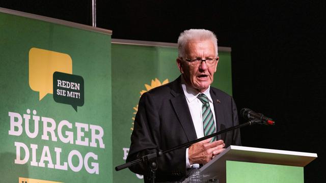 Winfried Kretschmann (Bündnis 90/Die Grünen), Ministerpräsident von Baden-Württemberg, steht auf einer Bühne und spricht während dem sogenannten Bürgerdialog seiner Fraktion zu den Anwesenden.
