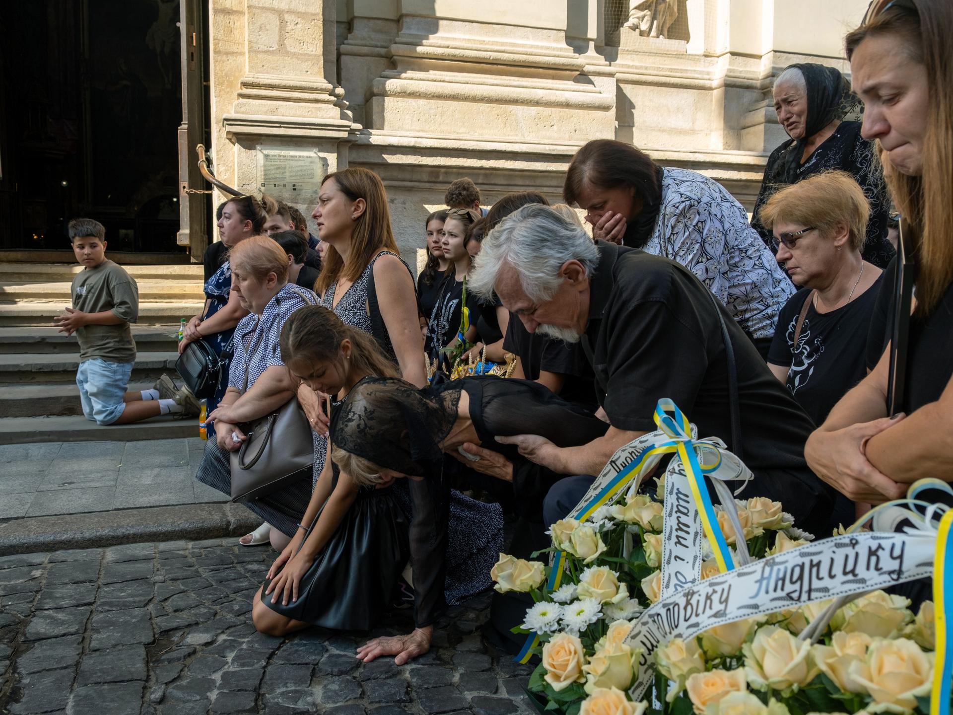 Beim Anblick der Särge fallen Angehörige und andere Anteilnehmende weinend auf die Knie. 