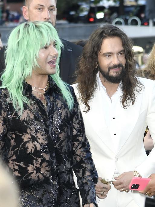 Die Brüder und Musiker der Band Tokio Hotel, Bill und Tom Kaulitz, stehen auf einem roten Teppich und sprechen mit Reportern.