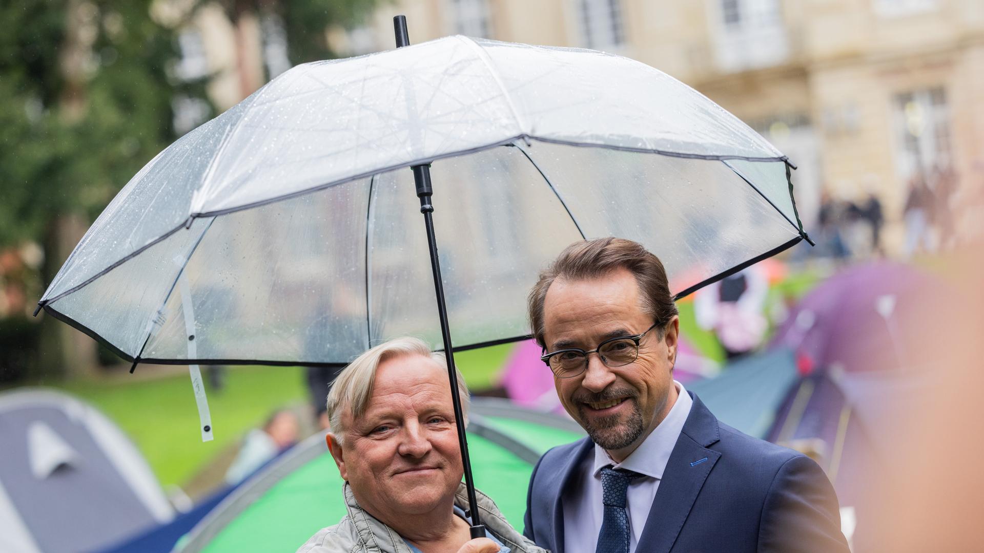 Axel Prahl (Hauptkommissar Frank Thiel, l), Schauspieler, und Jan Josef Liefers (Prof. Dr. Karl-Friedrich Boerne), Schauspieler, stehen am Set vom Münster «Tatort» zwischen Zelten im Park hinter dem Schloss. Die neue Episode «Ich gestehe» (AT) thematisiert Wohnungsnot unter Studierenden.