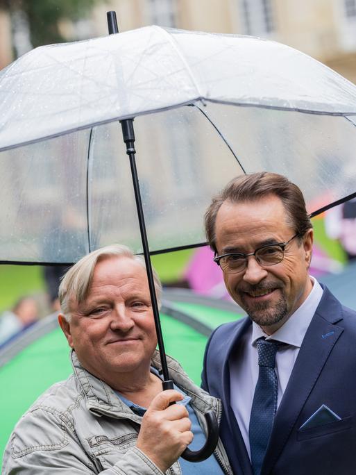 Axel Prahl (Hauptkommissar Frank Thiel, l), Schauspieler, und Jan Josef Liefers (Prof. Dr. Karl-Friedrich Boerne), Schauspieler, stehen am Set vom Münster «Tatort» zwischen Zelten im Park hinter dem Schloss. Die neue Episode «Ich gestehe» (AT) thematisiert Wohnungsnot unter Studierenden.