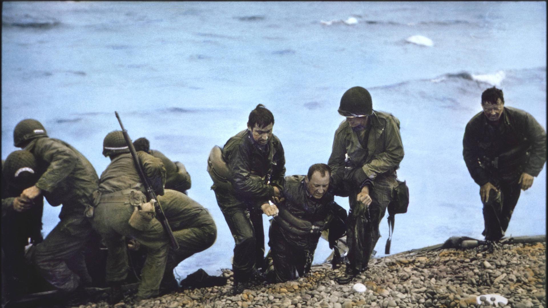 Mehrere alliierte Soldaten landen in Omaha-Beach. Ein Mann ist verletzt und wird von seinen Kameraden gestützt. Mehrere alliierte Soldaten landen in Omaha-Beach. Ein Mann ist verletzt und wird von seinen Kameraden gestützt.