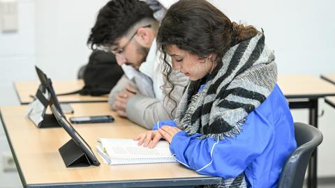 Cheima Dhouib (r.) und ein weiterer Schüler lesen während des islamischen Religionsunterrichts an einer Schule in Bonn am 7. Dezember 2022. Vor ihnen stehen Tablets auf dem Tisch.