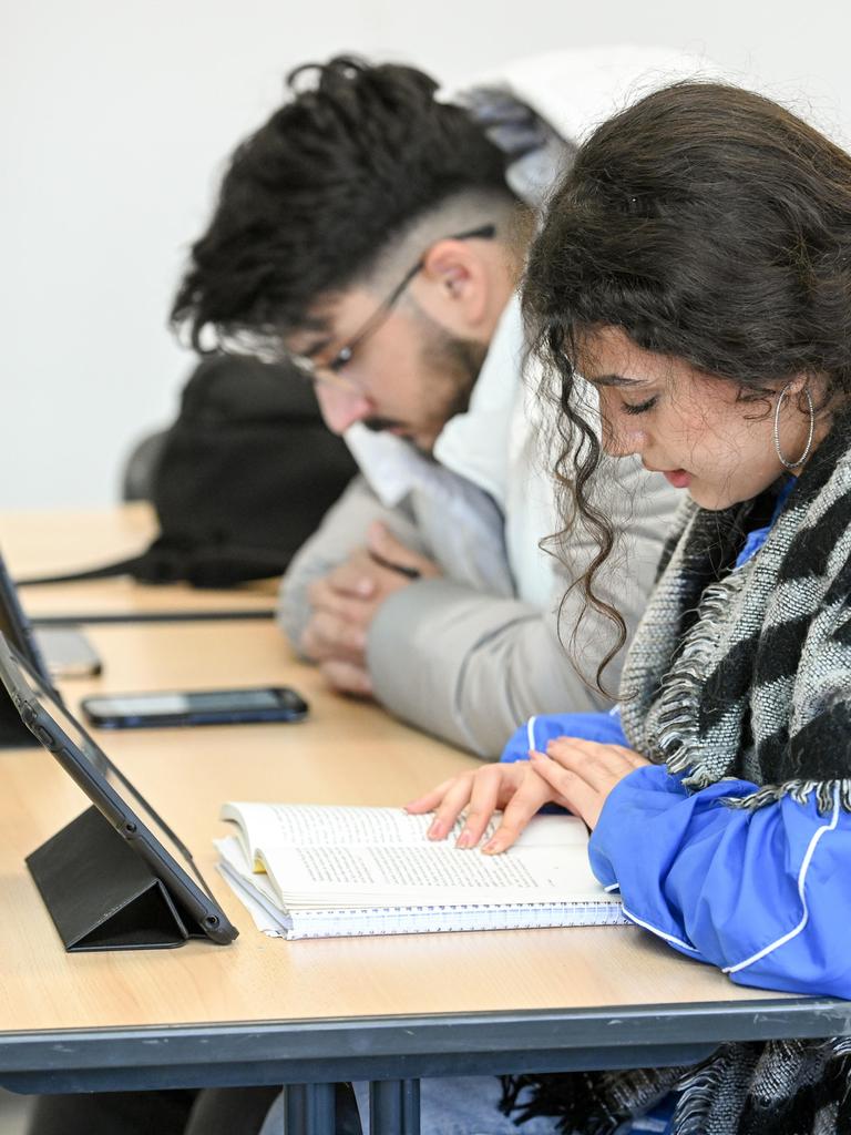 Cheima Dhouib (r.) und ein weiterer Schüler lesen während des islamischen Religionsunterrichts an einer Schule in Bonn am 7. Dezember 2022. Vor ihnen stehen Tablets auf dem Tisch.