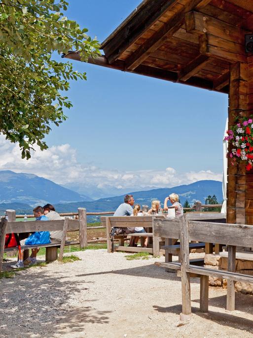 Touristen geniessen den Ausblick von der Tvon einer Almhütte in Südtirol. 