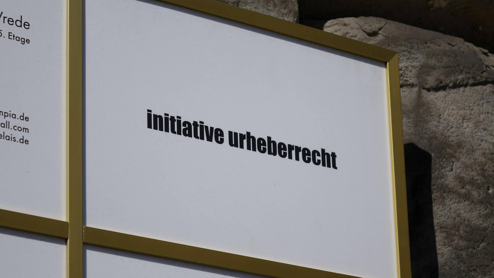 An einer Häuserwand hängt ein Schild mit dem Logo der Initiative Urheberrecht