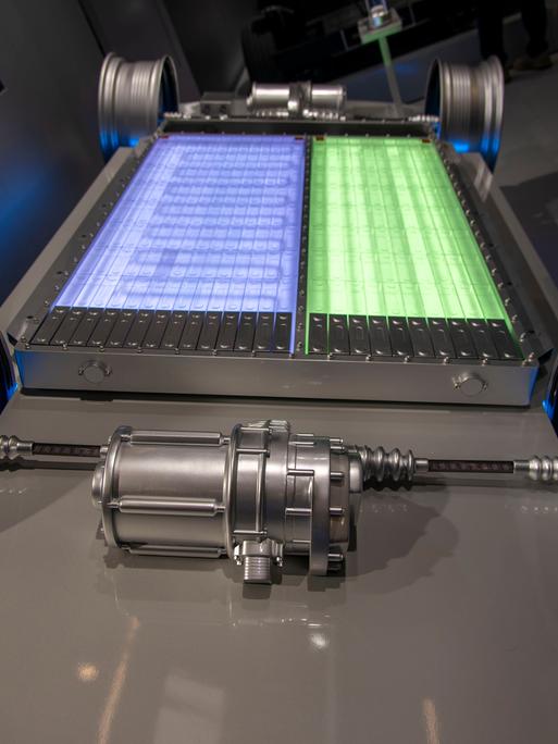 Zu sehen ist der Unterboden eines Elektrofahrzeugs ohne Karosserie, so dass die Batterie frei sichtbar ist. In der Mitte liegt ein großes, rechteckiges Batteriepaket, das aus zwei unterschiedlich farbigen Bereichen besteht. Zu sehen ist der Unterboden eines Elektrofahrzeugs ohne Karosserie, so dass die Batterie frei sichtbar ist. In der Mitte liegt ein großes, rechteckiges Batteriepaket, das aus zwei unterschiedlich farbigen Bereichen besteht.