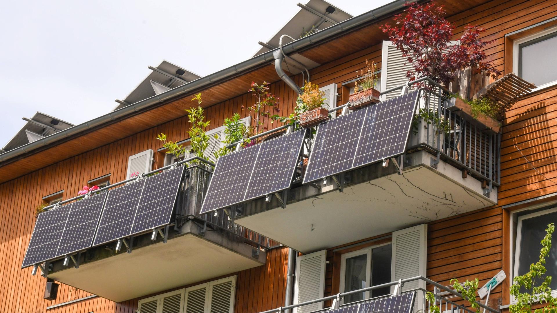 Solar-Anlagen an den Balkonen von einem Haus. Sie heißen auch Balkon-Kraftwerke. Die Solar-anlagen machen aus Sonnenlicht Strom. Ima