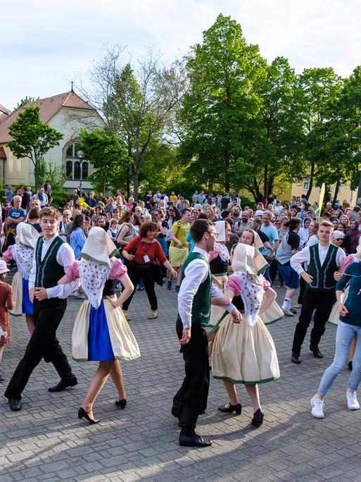 Happy Monday in Bautzen. Menschen in Trachten tanzen am 28.04.2024 unter freiem Himmel. Andere Menschen schauen zu.