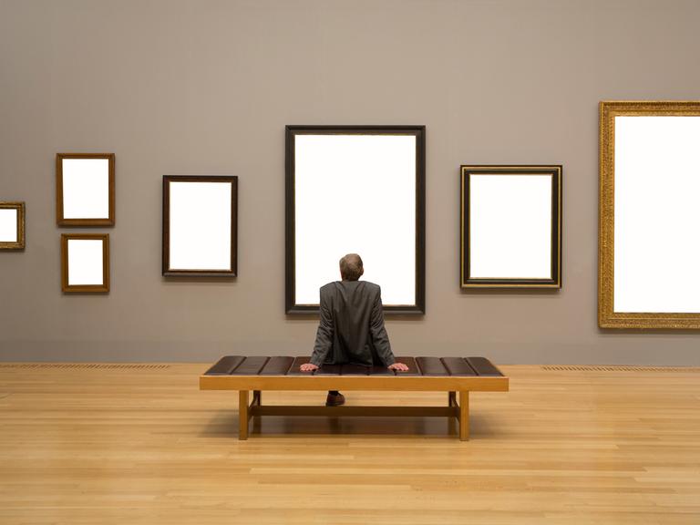 Ein Mann betrachtet leere Rahmen an einer Museumswand.