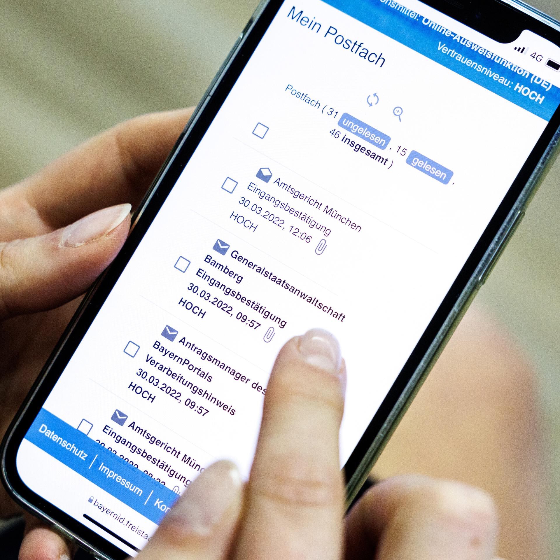 Eine Frau demonstriert bei einem Pressetermin zur Vorstellung von einem neuen Online-Zugang zum Einreichen von Klagen bei Gerichten das Prozedere zum Einreichen einer Klage über ihr Smartphone mittels der „BayernApp“.