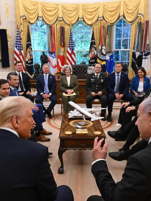 Rückenansicht von Donald Trump und Benjamin Netanjahu im Oval Office. Im Raum sitzen weiterhin ranghohe Funktionäre und Mitglieder der US-Regierung, darunter J. D. Vance