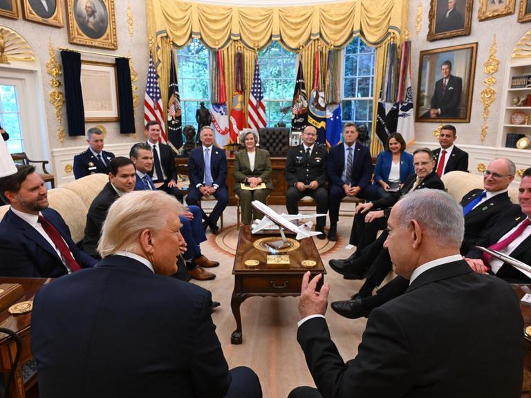Rückenansicht von Donald Trump und Benjamin Netanjahu im Oval Office. Im Raum sitzen weiterhin ranghohe Funktionäre und Mitglieder der US-Regierung, darunter J. D. Vance