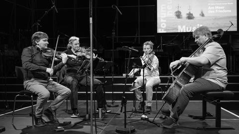 Das Asasello Quartett sitzt auf einer Bühne mit etlichen Mikrofonen und spielt konzentriert.