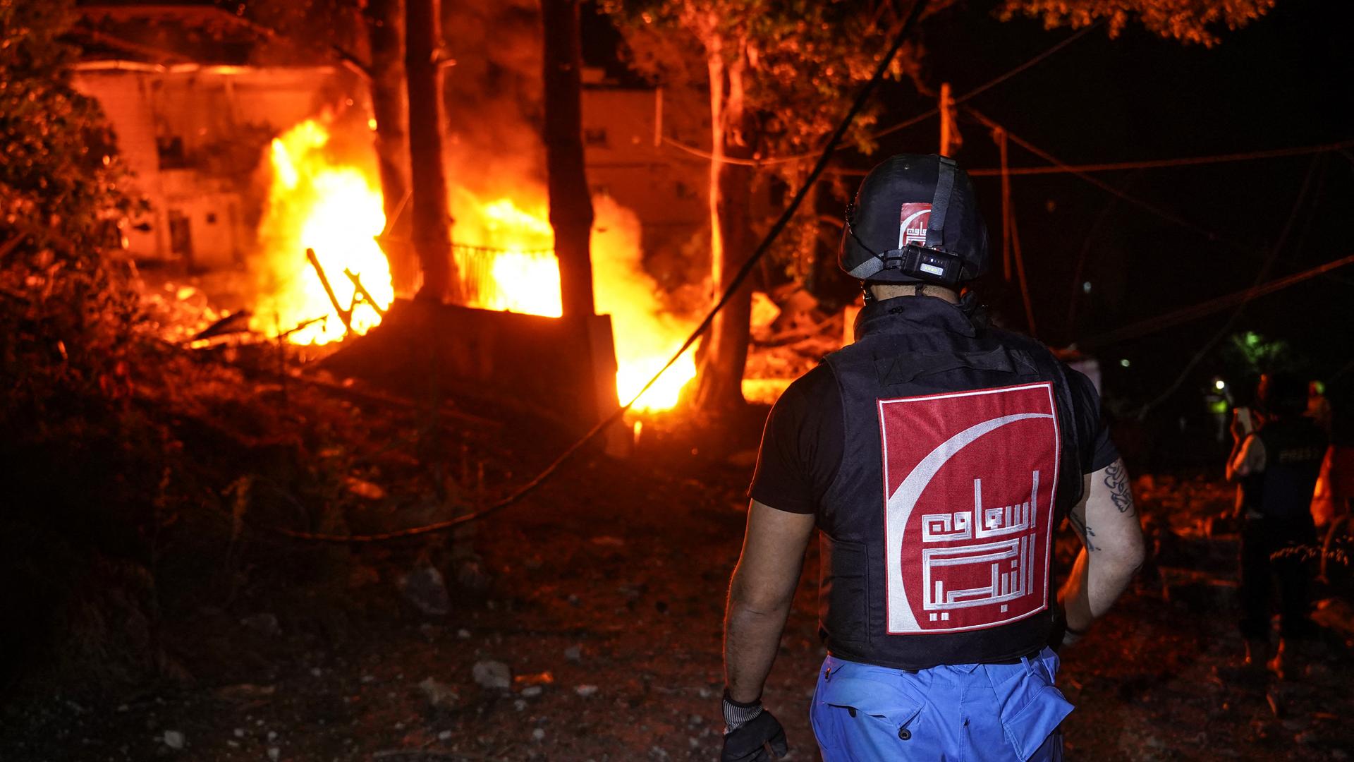 Ein Feuerwehrmann im Libanon steht vor einem brennenden Haus.