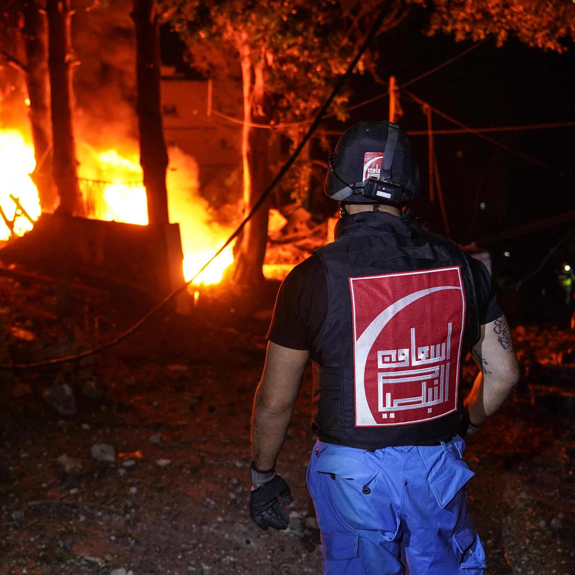 Ein Feuerwehrmann im Libanon steht vor einem brennenden Haus.