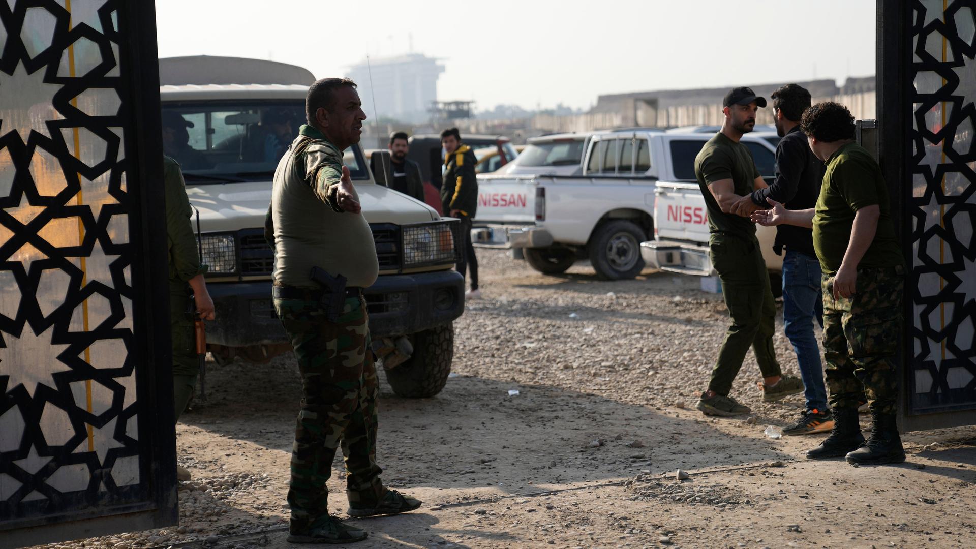 Irak, Bagdad: Mitglieder einer irakischen schiitischen militanten Gruppe stehen vor dem Hauptquartier der Popular Mobilization Force, nachdem es von einem Luftangriff getroffen wurde.