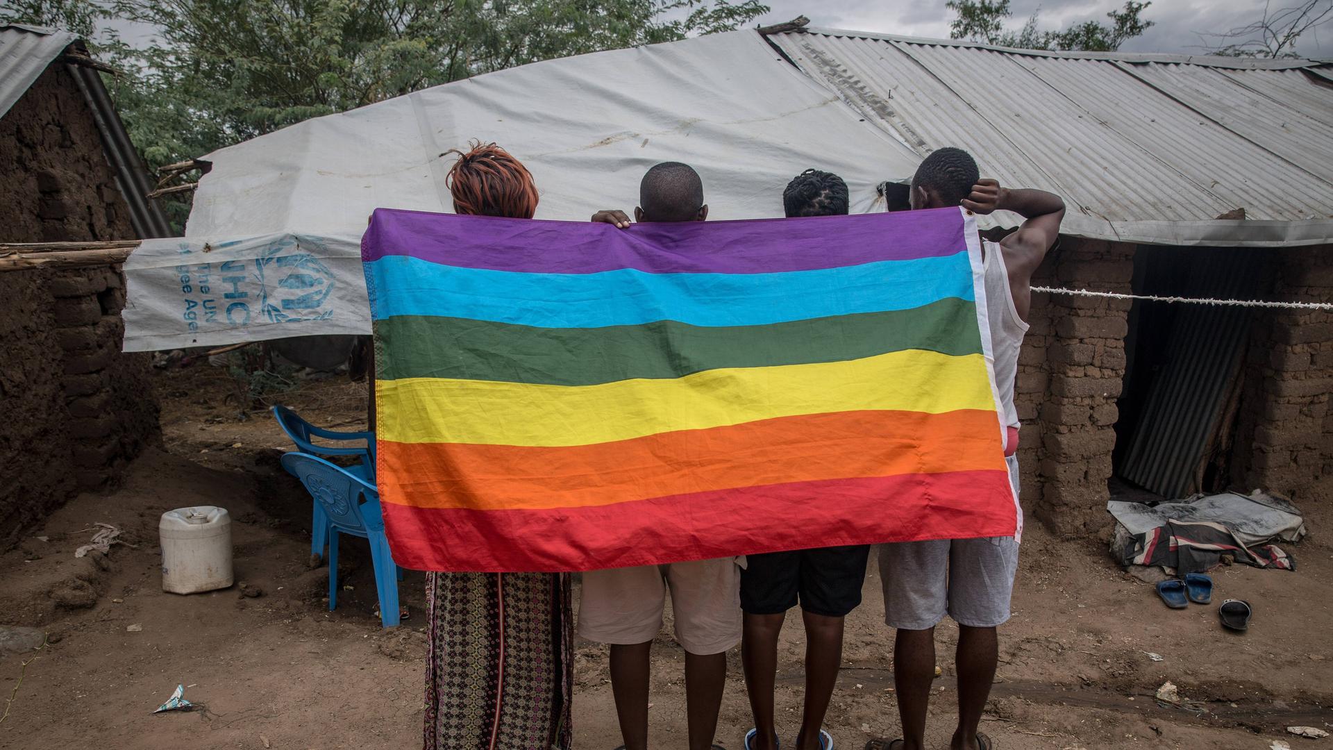 Flüchtlinge aus Uganda in einem Flüchtlingscamp im Nordwesten von Kenia. Sie halten eine auf den Kopf gedrehte Regenbogenflagge in den Händen.