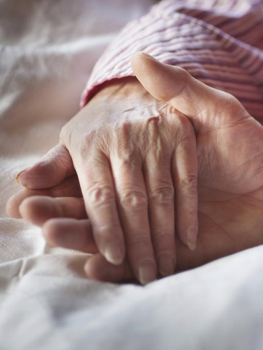 Eine Hand wird bei der Palliativpflege gehalten.