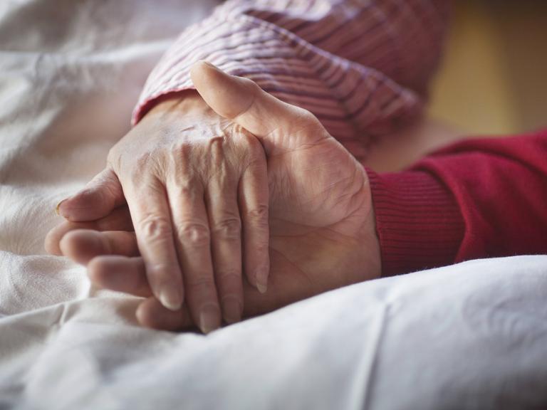Eine Hand wird bei der Palliativpflege gehalten.