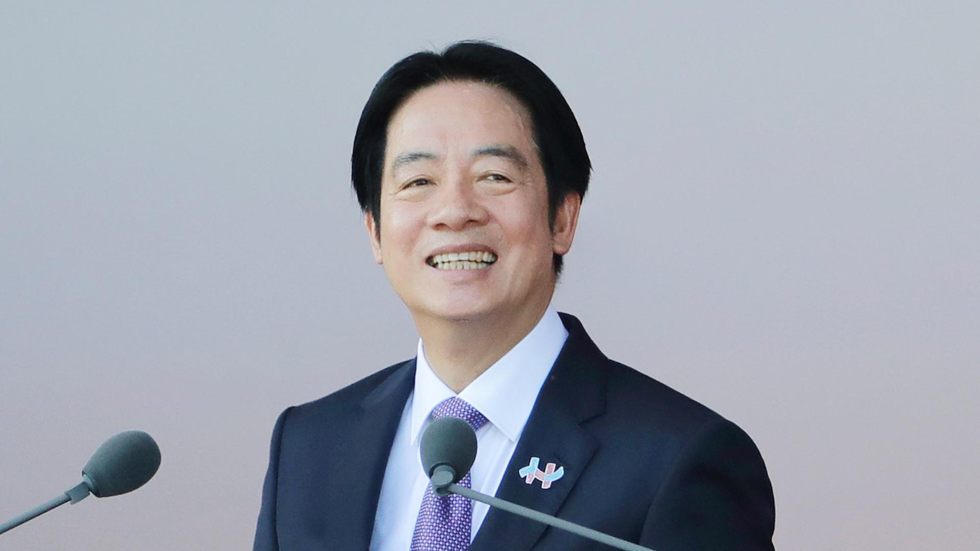 Der taiwanesische Präsident Lai Ching-te hält eine Rede. Er steht vor Mikrofonen und lächelt in die Kamera.