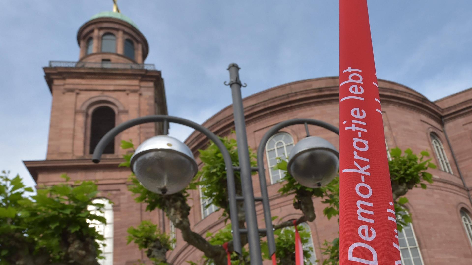 Vor der Frankfurter Paulskirche weht zum Paulskirchenfest 2023, das den 175. Jahrestag der Zusammenkunft der Nationalversammlung in der Paulskirche 1848 feiert, eine Fahne mit der Aufschrift "Demo-kra-tie lebt".