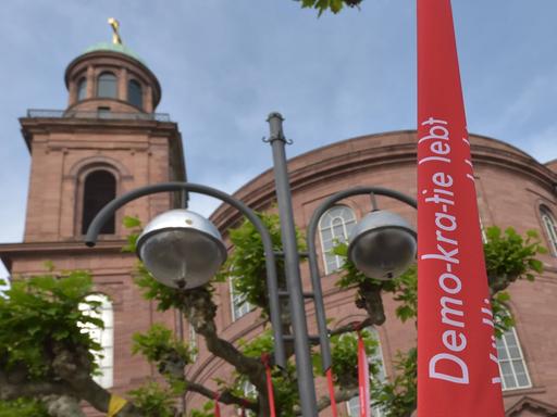 Vor der Frankfurter Paulskirche weht zum Paulskirchenfest 2023, das den 175. Jahrestag der Zusammenkunft der Nationalversammlung in der Paulskirche 1848 feiert, eine Fahne mit der Aufschrift "Demo-kra-tie lebt".