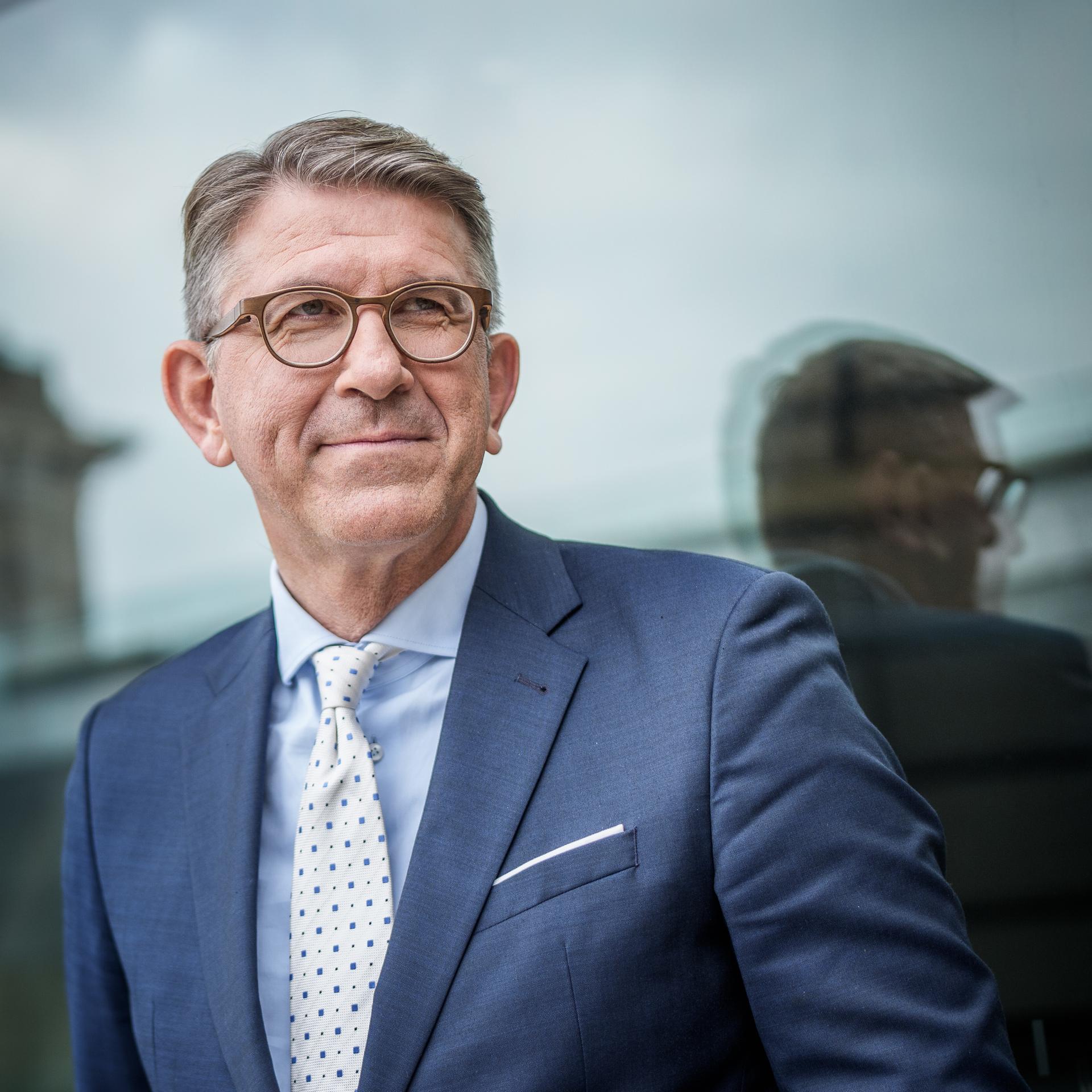 Wolfram Weimer trägt ein weißes Hemd, blaues Sakko und schaut freundlich zur Seite. 