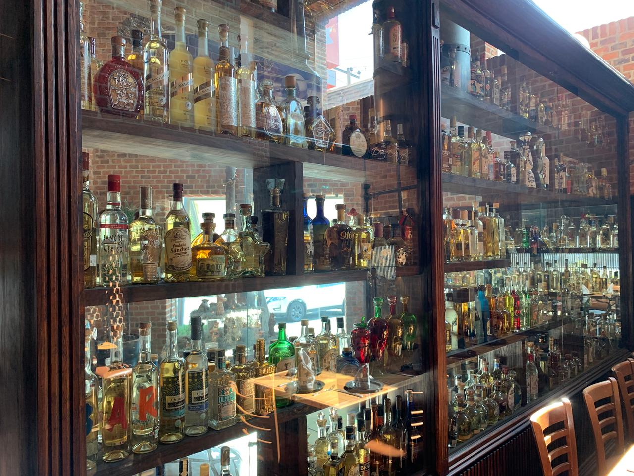 Eine große Regalwand mit Dutzenden mit Alkoholika gefüllten bunten Glasflaschen in mehreren Reihen.