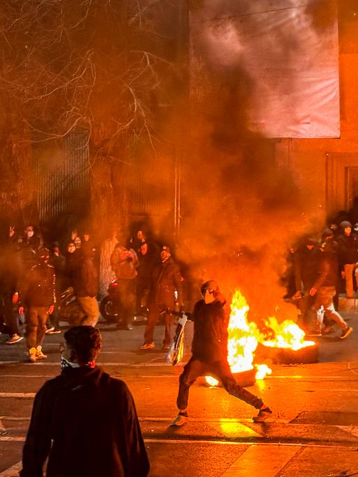 Protestierende haben eine nächtliche Straße in Teheran mit brennenden Autoreifen blockiert.