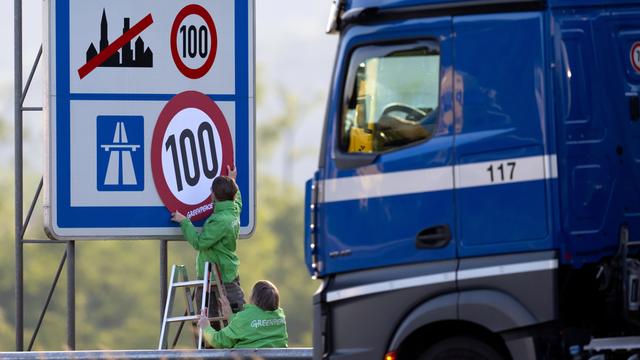 Aktivisten von Greenpeace überkleben an der Autobahn ein Hinweisschild mit den Tempolimits.
