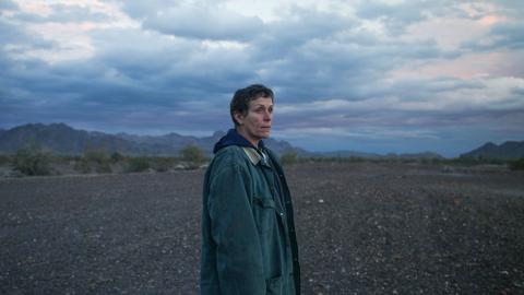 Blick in eine ungewisse Zukunft: Frances McDormand im Fillm Nomadland. Im Hintergrund ist der weite Himmel zu sehen, eine Frau blickt aus dem Bild heraus in die Ferne. 
