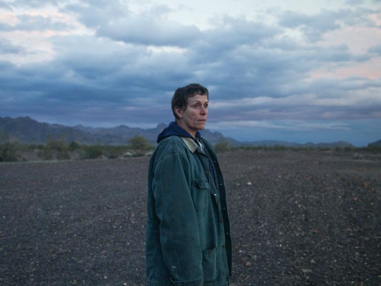 Blick in eine ungewisse Zukunft: Frances McDormand im Fillm Nomadland. Im Hintergrund ist der weite Himmel zu sehen, eine Frau blickt aus dem Bild heraus in die Ferne. 