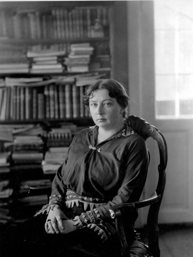 Die Literaturpreisträgerin von 1928, die norwegische Schriftstellerin Sigrid Undset, sitzt in diesem Schwarz-weiß-Foto in einem Lehnstuhl und blickt in die Kamera. Im Hintergrund ist ein Bücherregal zu erkennen.