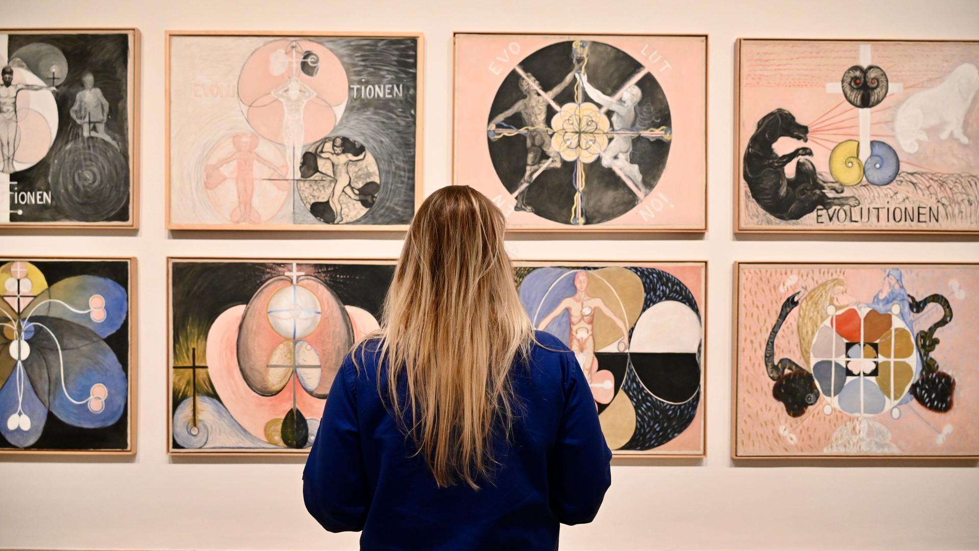 Eine Betrachterin steht vor Gemälden von Hilma af Klint in London.